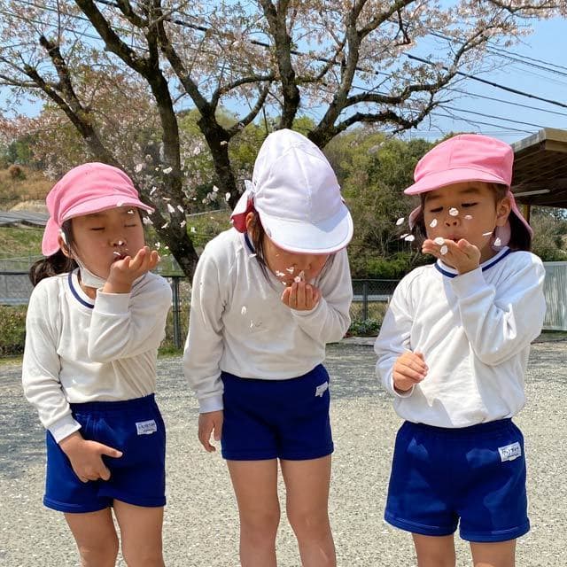 真木保育園の年長さん３人で桜の花びらを吹いてポーズ